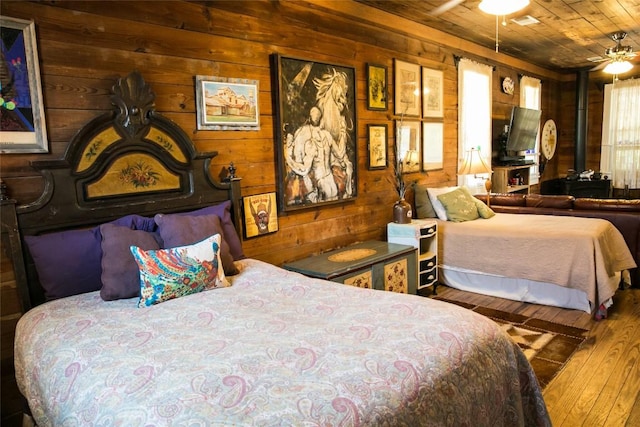 bedroom featuring wooden walls, ceiling fan, wooden ceiling, and hardwood / wood-style flooring