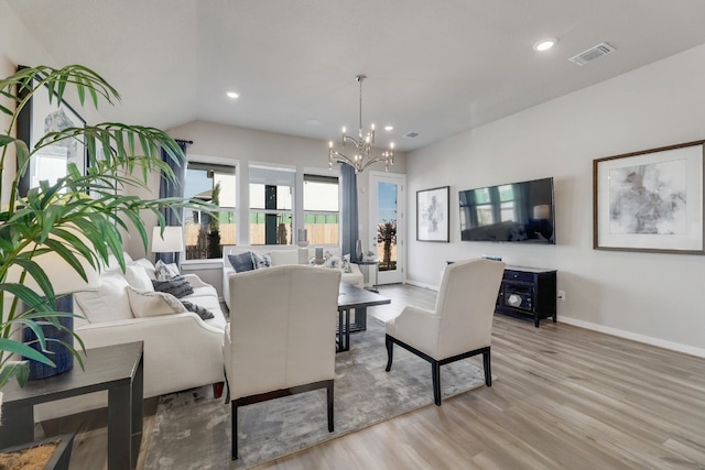 living room with light hardwood / wood-style floors, lofted ceiling, and an inviting chandelier