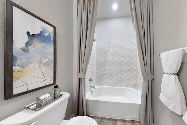 bathroom featuring wood-type flooring,  shower combination, and toilet