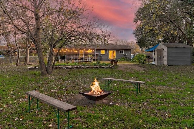 yard at dusk featuring a fire pit and a storage unit