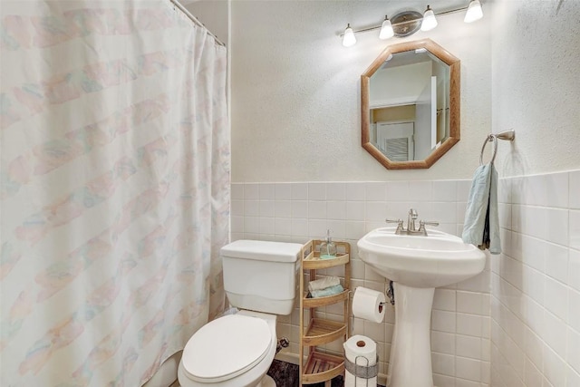 bathroom featuring a shower with shower curtain, toilet, tile walls, and sink