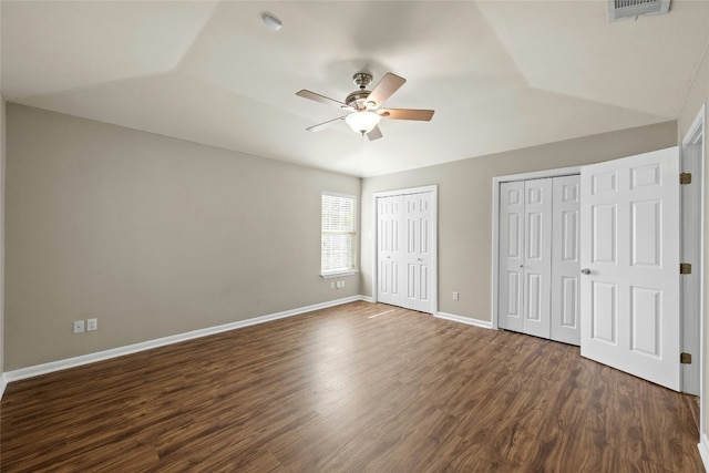 unfurnished bedroom with multiple closets, ceiling fan, dark hardwood / wood-style flooring, and lofted ceiling