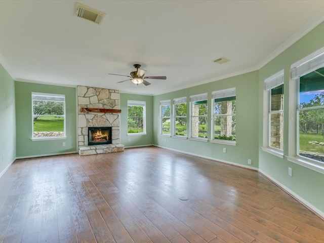 unfurnished living room featuring a stone fireplace, ceiling fan, crown molding, and hardwood / wood-style flooring