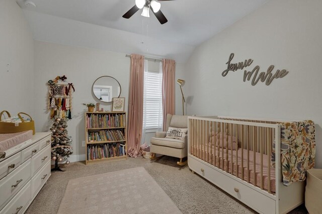 carpeted bedroom with ceiling fan, a crib, and vaulted ceiling