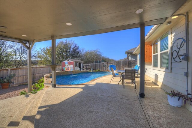 view of patio / terrace featuring a fenced in pool, pool water feature, and a shed