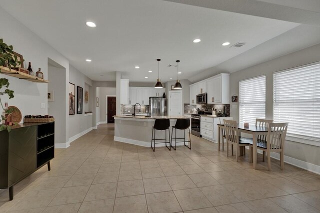 kitchen featuring sink, hanging light fixtures, a center island with sink, white cabinets, and appliances with stainless steel finishes