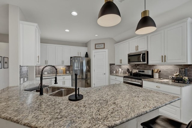 kitchen with kitchen peninsula, sink, appliances with stainless steel finishes, decorative light fixtures, and white cabinetry