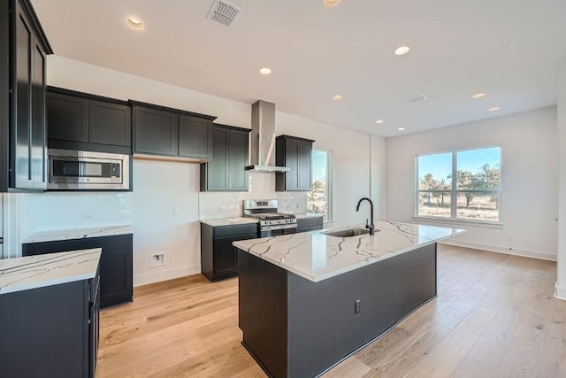 kitchen featuring stainless steel appliances, sink, a kitchen island with sink, and wall chimney exhaust hood