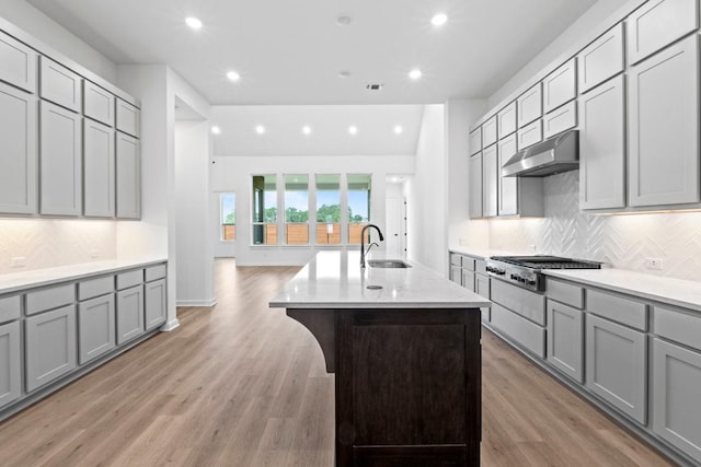 2120 Tobiano Trce, Georgetown, TX 78633 - kitchen with gray cabinetry, under cabinet range hood, stainless steel gas stovetop, recessed lighting, and a sink