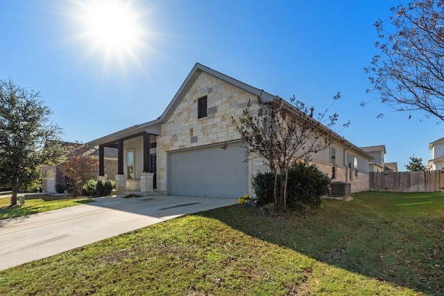 view of front of property featuring central AC unit, a garage, and a front lawn