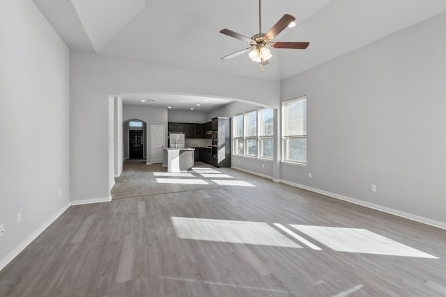 unfurnished living room featuring light hardwood / wood-style floors, high vaulted ceiling, and ceiling fan