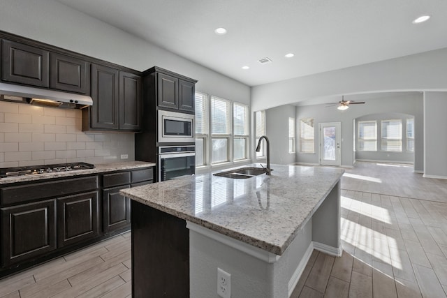 kitchen with decorative backsplash, sink, an island with sink, and stainless steel appliances