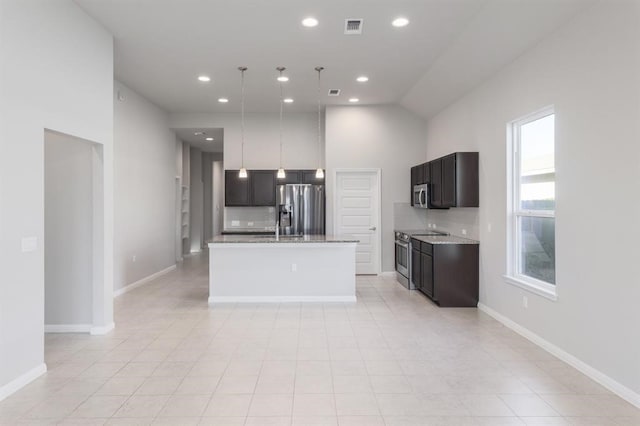 kitchen with light stone countertops, a center island, hanging light fixtures, stainless steel appliances, and tasteful backsplash