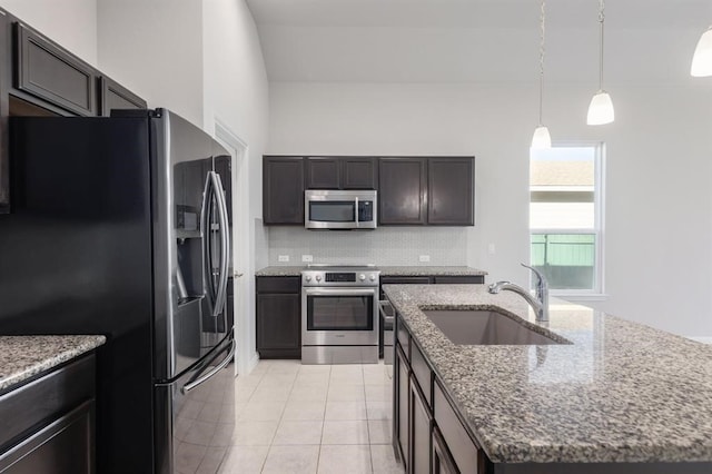 kitchen with appliances with stainless steel finishes, backsplash, dark stone counters, a kitchen island with sink, and sink