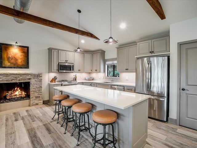 kitchen with a kitchen bar, a stone fireplace, a center island, and stainless steel appliances