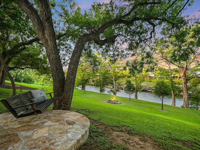 yard at dusk with a water view and a patio