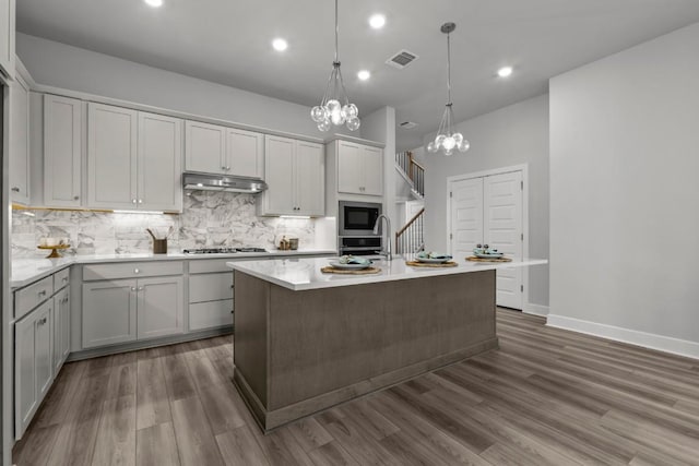 6304 Rotunda Vw, Austin, TX 78747 - kitchen with built in microwave, a chandelier, under cabinet range hood, backsplash, and light countertops