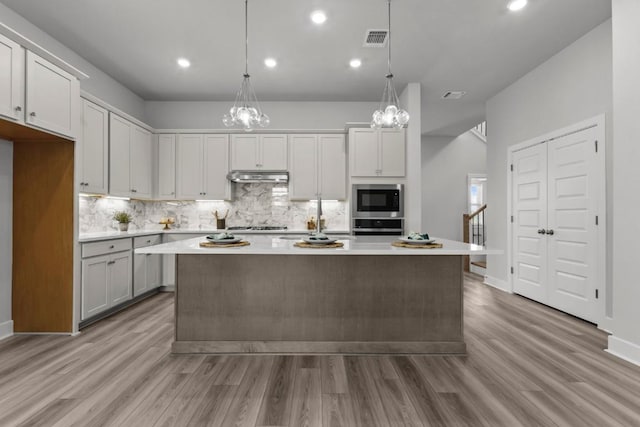6304 Rotunda Vw, Austin, TX 78747 - kitchen with appliances with stainless steel finishes, under cabinet range hood, light countertops, decorative backsplash, and light wood-type flooring