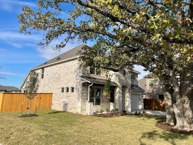 view of side of property with a garage, fence, a lawn, and brick siding