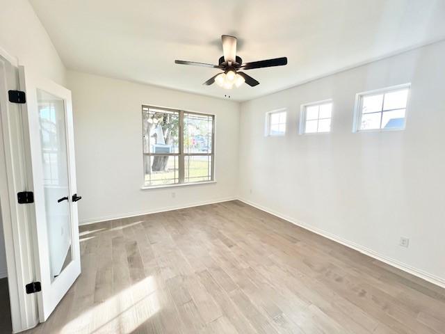 empty room featuring ceiling fan, a wealth of natural light, and light hardwood / wood-style flooring