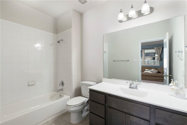 full bathroom featuring tile patterned flooring, tiled shower / bath combo, toilet, and vanity