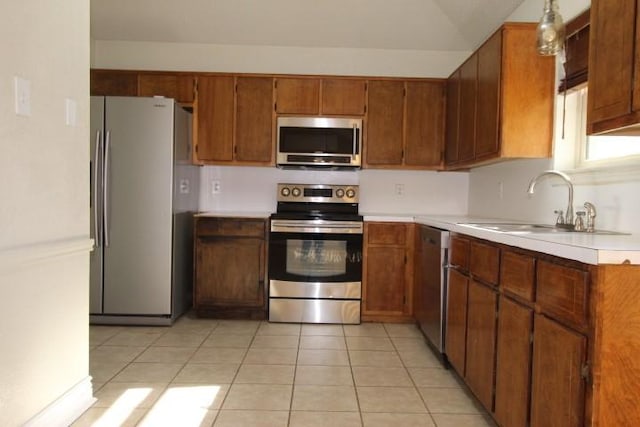 kitchen with sink, light tile patterned flooring, stainless steel appliances, and decorative light fixtures