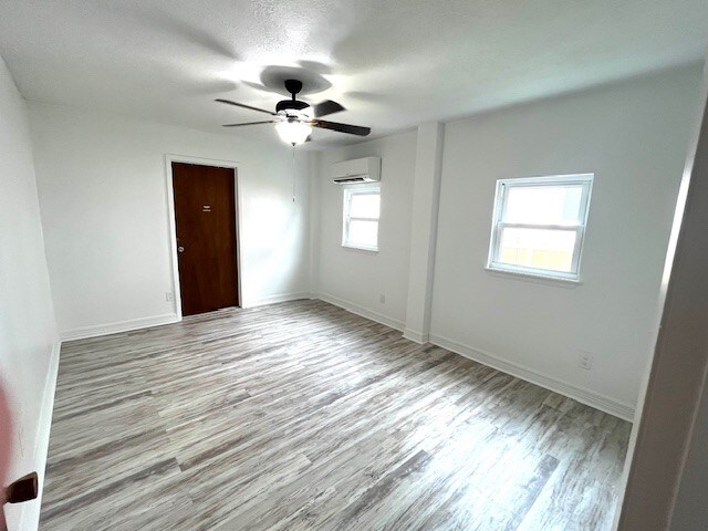 246 Starboard Ave, Rockport, TX 78382 - empty room with a wall mounted AC, wood finished floors, ceiling fan, and baseboards