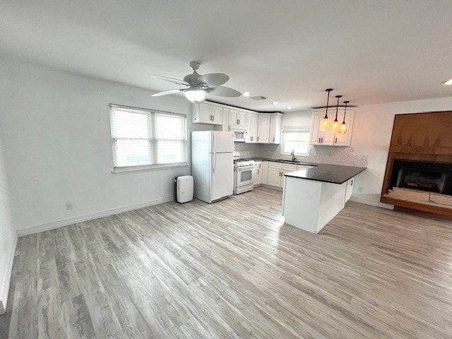 246 Starboard Ave, Rockport, TX 78382 - kitchen featuring white appliances, a peninsula, open floor plan, a sink, and dark countertops