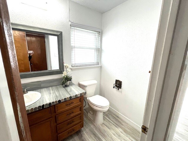 246 Starboard Ave, Rockport, TX 78382 - half bathroom with wood finished floors, toilet, vanity, and baseboards
