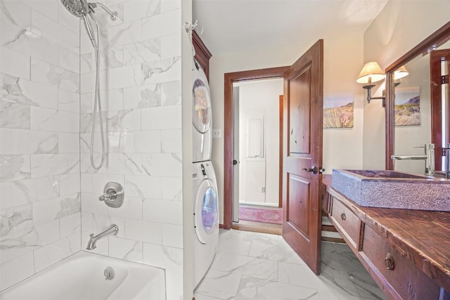 bathroom with stacked washer and dryer, vanity, and tiled shower / bath combo