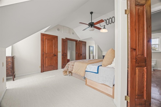 carpeted bedroom with ceiling fan, lofted ceiling, and ensuite bathroom