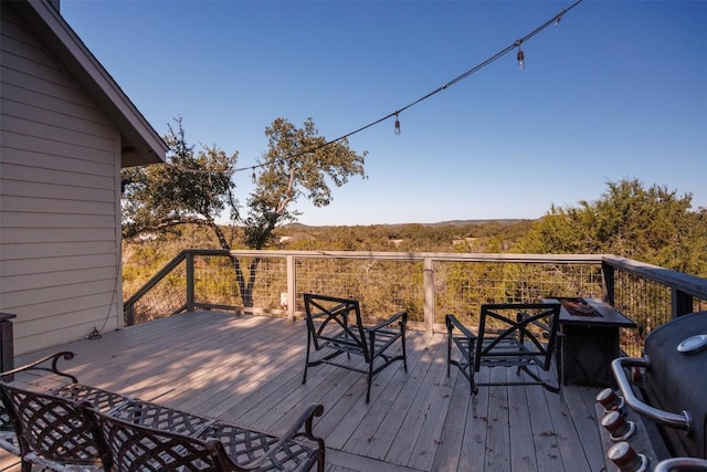 wooden deck featuring area for grilling and an outdoor fire pit