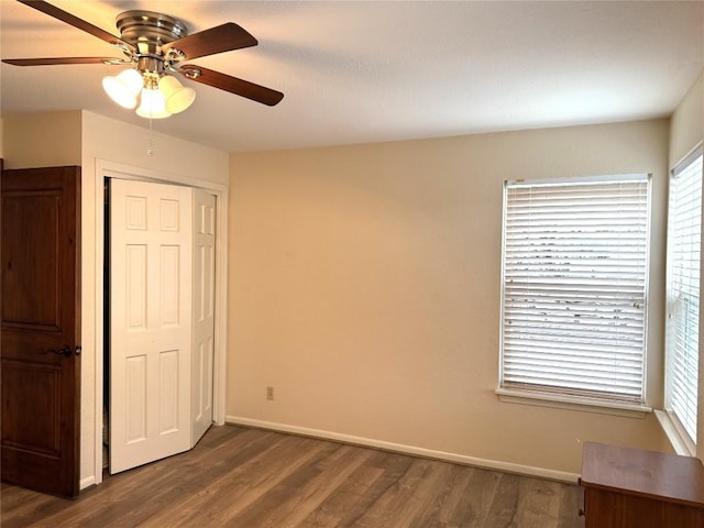 unfurnished bedroom featuring ceiling fan, a closet, and dark wood-type flooring