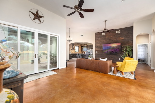 living room with ceiling fan, concrete flooring, and a towering ceiling