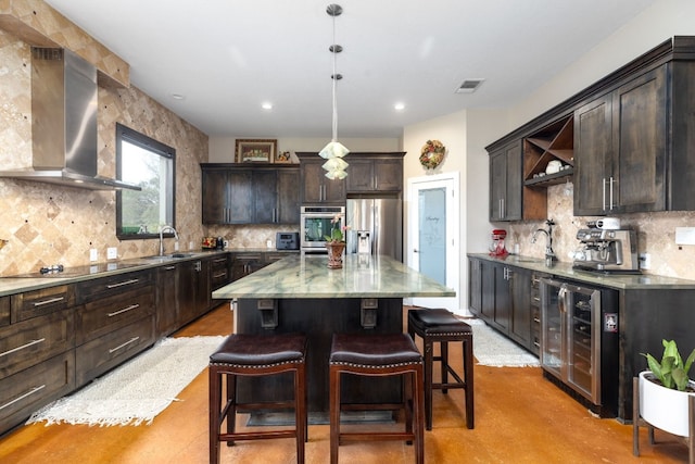 kitchen featuring sink, wall chimney range hood, stainless steel fridge, decorative light fixtures, and a kitchen island