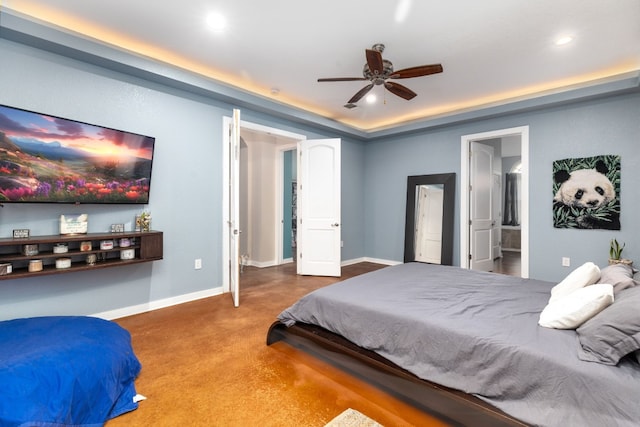 bedroom featuring a tray ceiling, connected bathroom, and ceiling fan