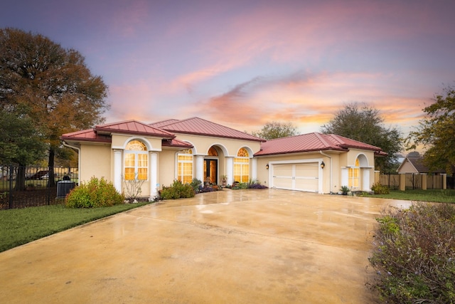 mediterranean / spanish house with a yard, central AC, and a garage