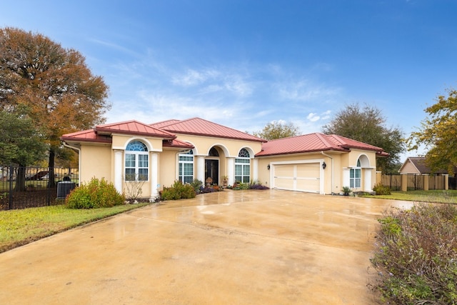 mediterranean / spanish home featuring central air condition unit and a garage