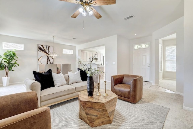 living room featuring ceiling fan with notable chandelier and light colored carpet