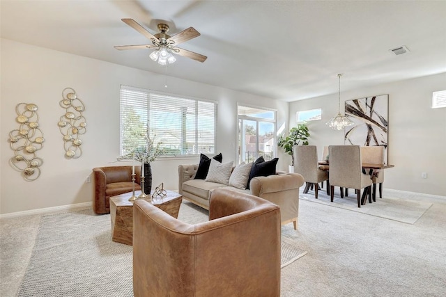 living room featuring light carpet and ceiling fan with notable chandelier