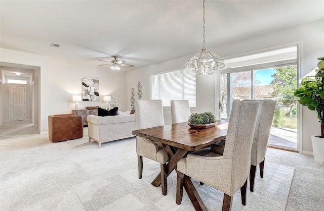 dining area featuring ceiling fan with notable chandelier and light carpet