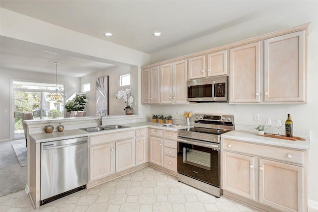 kitchen with kitchen peninsula, pendant lighting, stainless steel appliances, and sink