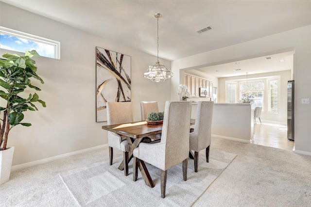 dining area featuring light carpet and an inviting chandelier