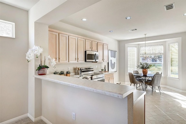 kitchen featuring decorative light fixtures, light brown cabinets, kitchen peninsula, and appliances with stainless steel finishes