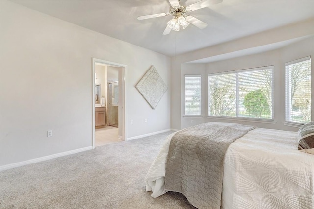 bedroom featuring ceiling fan, light colored carpet, and ensuite bathroom