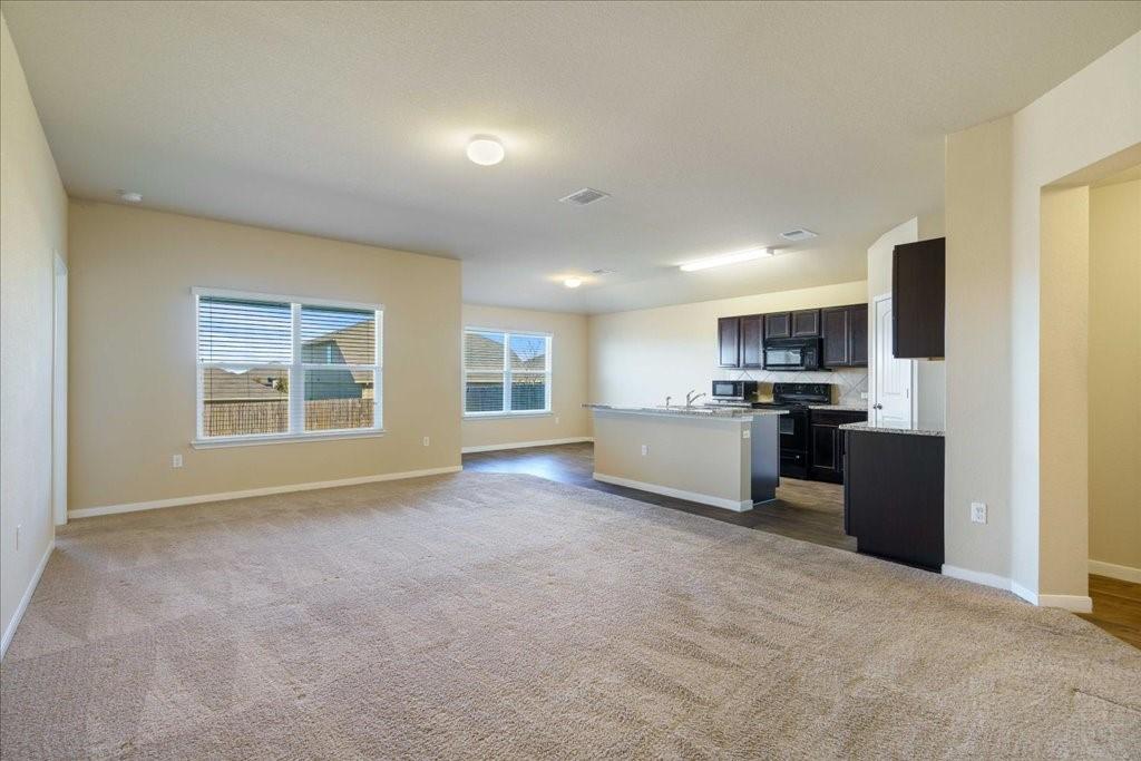 kitchen featuring carpet flooring, a kitchen island with sink, and black appliances