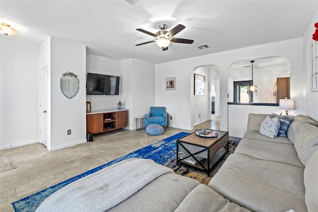 living room with ceiling fan with notable chandelier