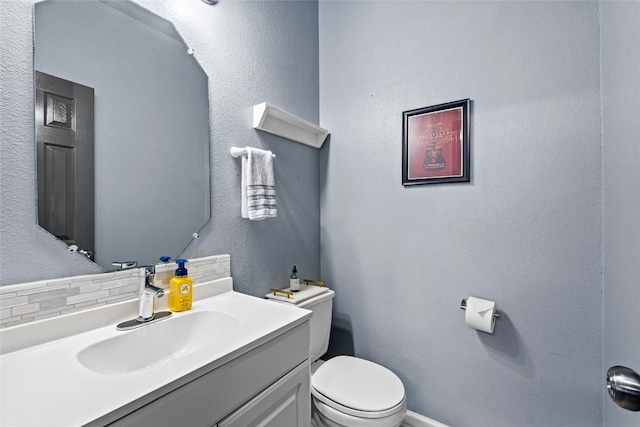 bathroom with vanity, tasteful backsplash, and toilet