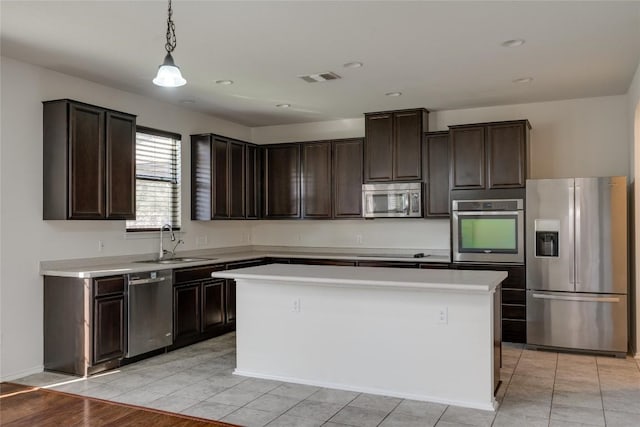 kitchen with sink, stainless steel appliances, pendant lighting, dark brown cabinets, and a kitchen island