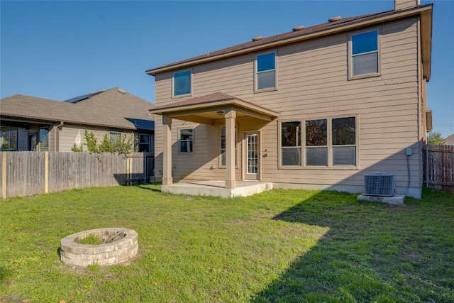 rear view of property featuring a lawn, central AC unit, an outdoor fire pit, and a patio